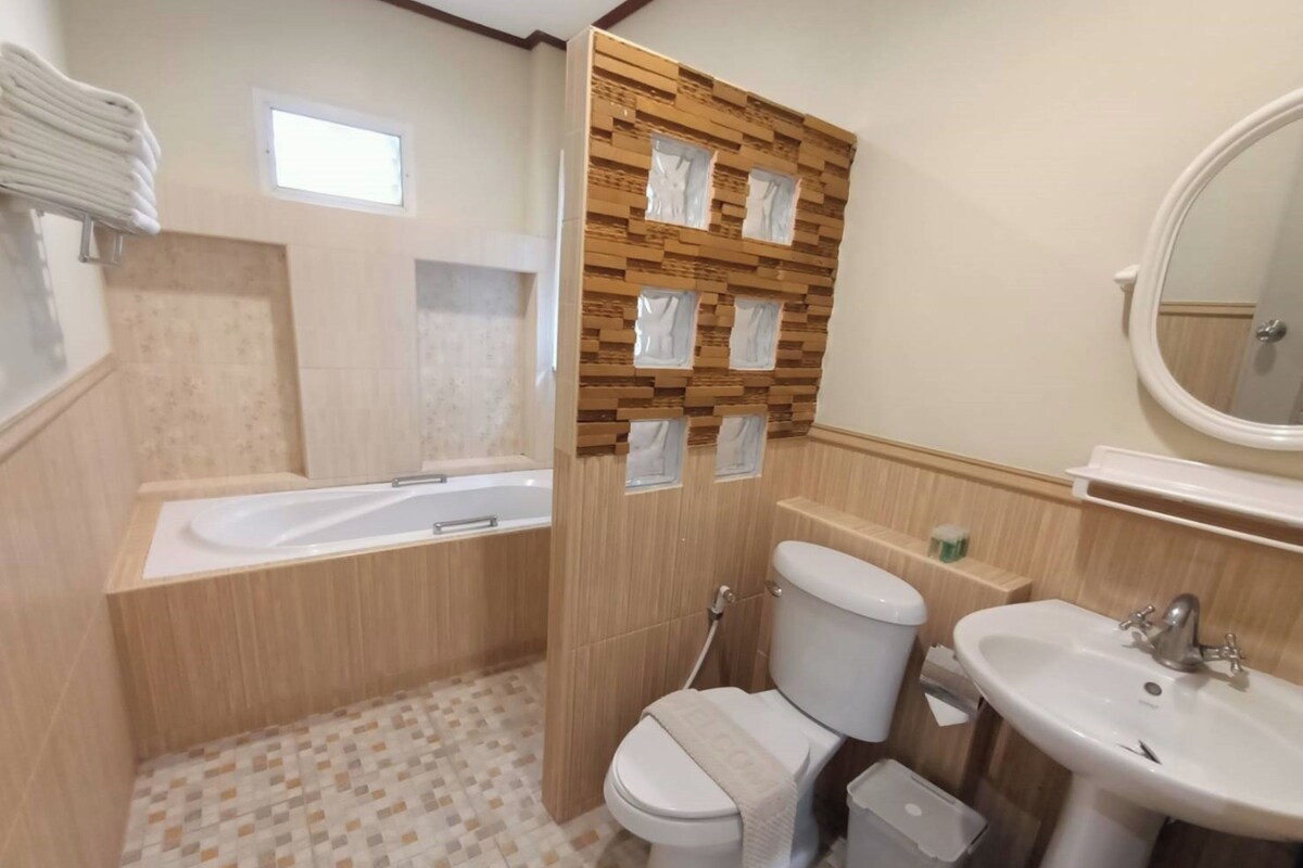 Un baño con bañera, inodoro, lavamanos y espejo.