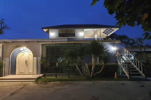 Un edificio moderno con una amplia fachada de vidrio, un acceso cubierto y una escalera que lleva a un nivel superior.