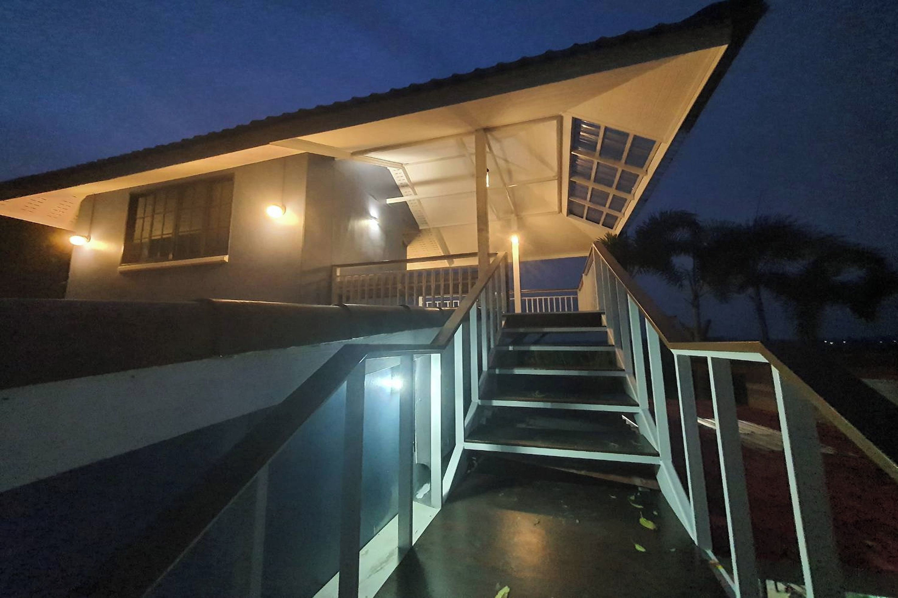 A staircase leading to a building with a sloped roof and a covered area with windows.