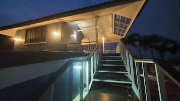 A staircase leading to a building with a sloped roof and a covered area with windows.