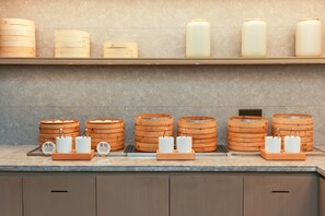 A kitchen counter with various containers and utensils, including wooden chafing dishes and white ceramic containers, likely for food preparation. - Ji Hotel Shanghai Xujiahui Caobao Road Subway Stat (Shanghai)