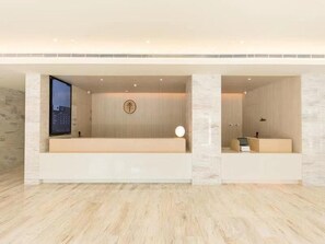 A modern hotel lobby with a reception desk, a seating area, and a wall-mounted screen. - JI Hotel(hangzhou Sandun West Lake Science and Tec (Hangzhou)
