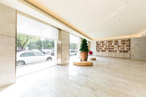 Un amplio vestíbulo con ventanas grandes, una planta central y un mueble de estanterías moderno.