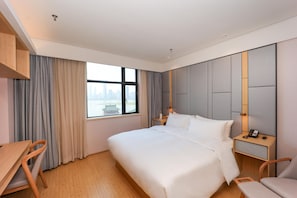 A modern hotel room with a large bed, bedside tables, a desk, and a chair. - Ji Hotel (Nanchang)