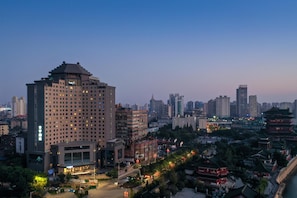 Un hotel de gran altura con varios pisos, rodeado por un paisaje urbano con edificios diversos y un río.