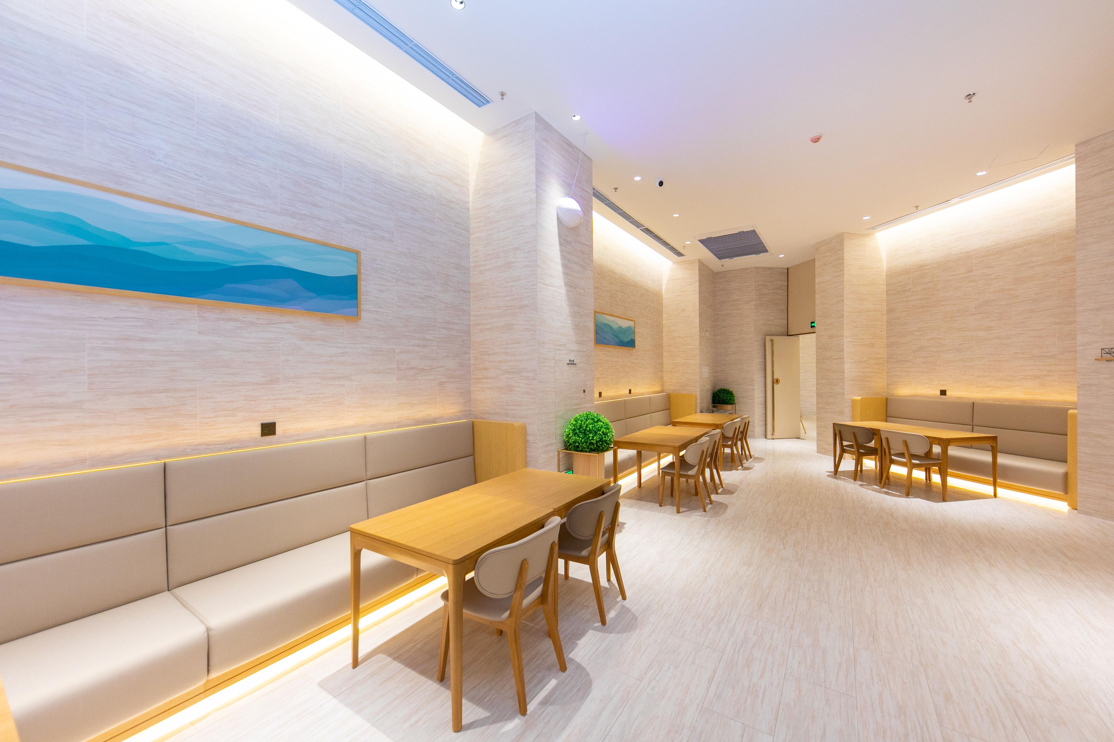 Un hall d’hôtel moderne avec un long comptoir d’accueil, des espaces de détente et un grand tableau accroché au mur.