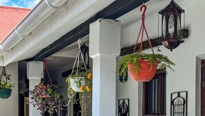A white building with a balcony, hanging plants, and decorative lanterns. - Emerald Palm Courtyard Hotel (Zanzibar Town)