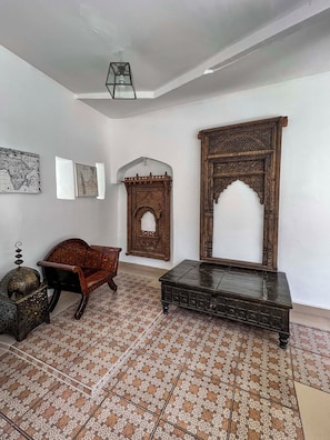 A room with a patterned floor, a wooden bench, a decorative wooden screen, and a wall-mounted map. - Emerald Palm Courtyard Hotel (Zanzibar Town)