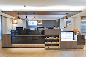 A modern reception desk with a digital display, wooden accents, and a coffee display.