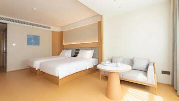 A modern hotel room with a large bed, a sofa, a round table, and a view of the city.