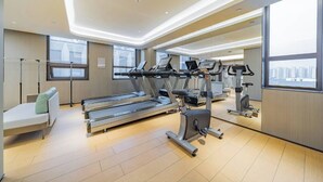 Un gimnasio moderno con cintas de correr, elípticas y una banca.
