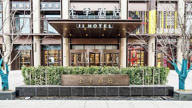 Entrada de un hotel con un cartel que dice 'JI HOTEL' y una placa en la puerta.