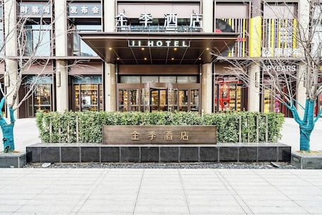 A hotel entrance with a sign reading 'JI HOTEL' and a nameplate in front.. Ji Hotel
