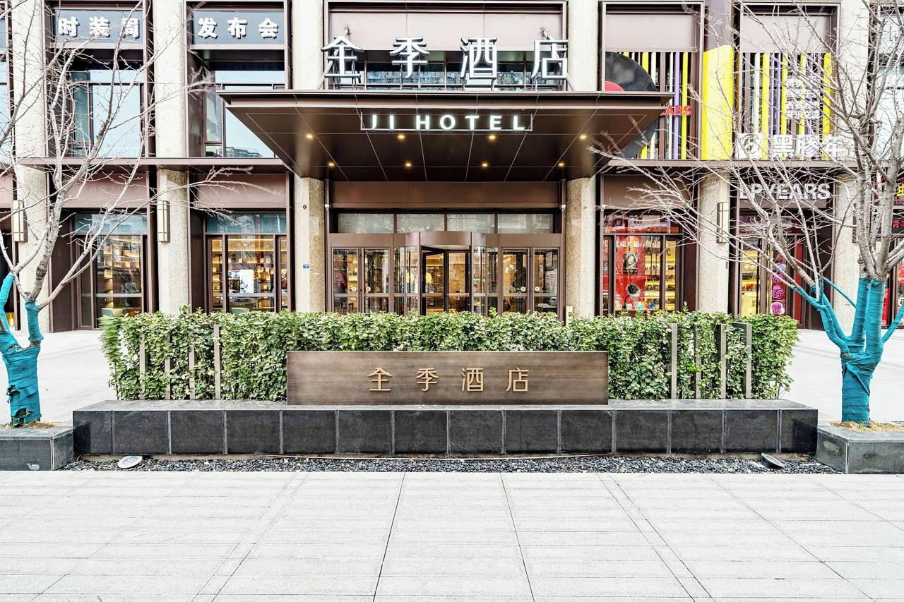 A hotel entrance with a sign reading 'JI HOTEL' and a nameplate in front.