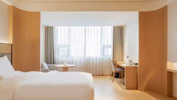 A hotel room with two beds, a desk, and a chair.
