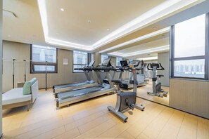 A modern gym with treadmills, elliptical machines, and a bench.