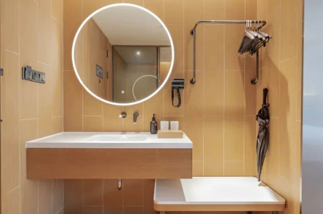 A modern bathroom with a large mirror, a sink, a towel rack, and a shower area.