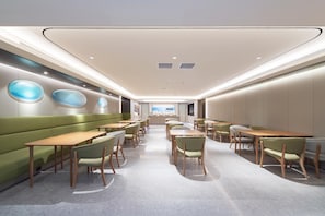 A modern restaurant with green booths, wooden tables, and chairs. - Ji Hotel (dalian Xinghai Convention and Exhibition (Dalian)