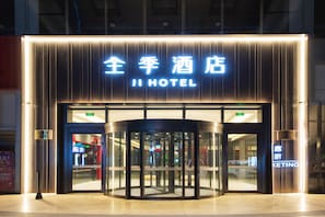 A hotel entrance with a revolving door, illuminated signage, and a visible KFC outlet in the background. - Ji Hotel (dalian Xinghai Convention and Exhibition (Dalian)