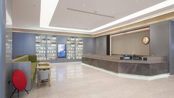 Un lobby moderno de hotel con mostrador de recepción, zona de estar y pantalla digital.
