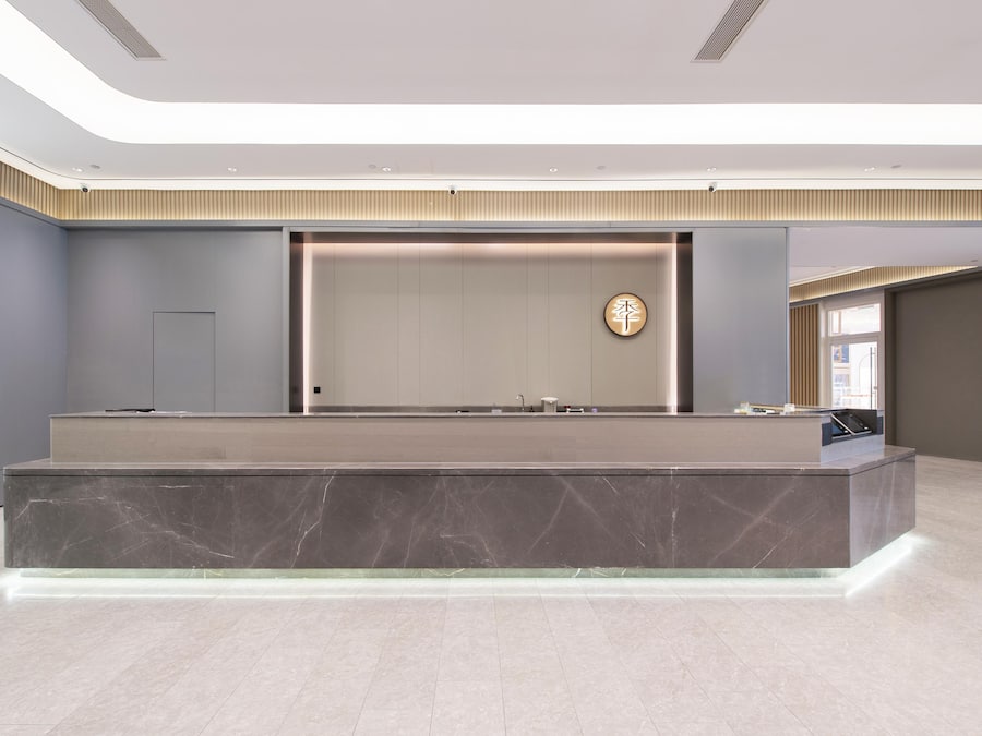 A modern reception area with a marble counter, a wall-mounted clock, and a large window.