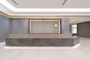 A modern reception area with a marble counter, a wall-mounted clock, and a large window. - Ji Hotel (dalian Xinghai Convention and Exhibition (Dalian)