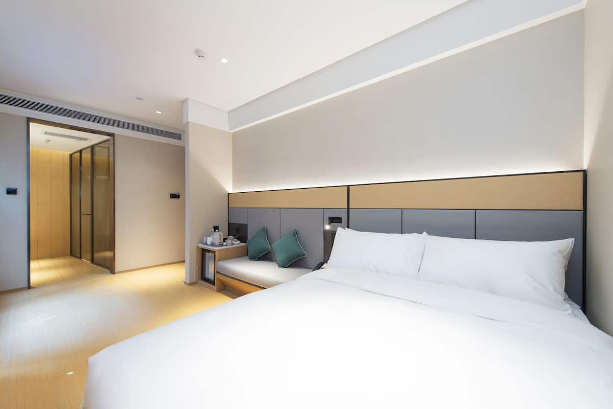 Una habitación de hotel moderna con una cama grande, una mesita de noche y un armario empotrado.
