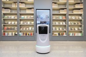 A self-service kiosk with a digital screen, surrounded by shelves of books and magazines. - Ji Hotel (dalian Xinghai Convention and Exhibition (Dalian)