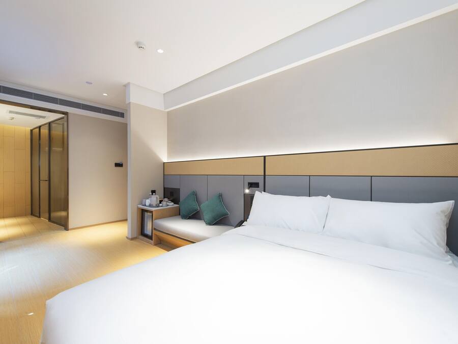 Una habitación de hotel moderna con una cama grande, una mesita de noche y un armario empotrado.
