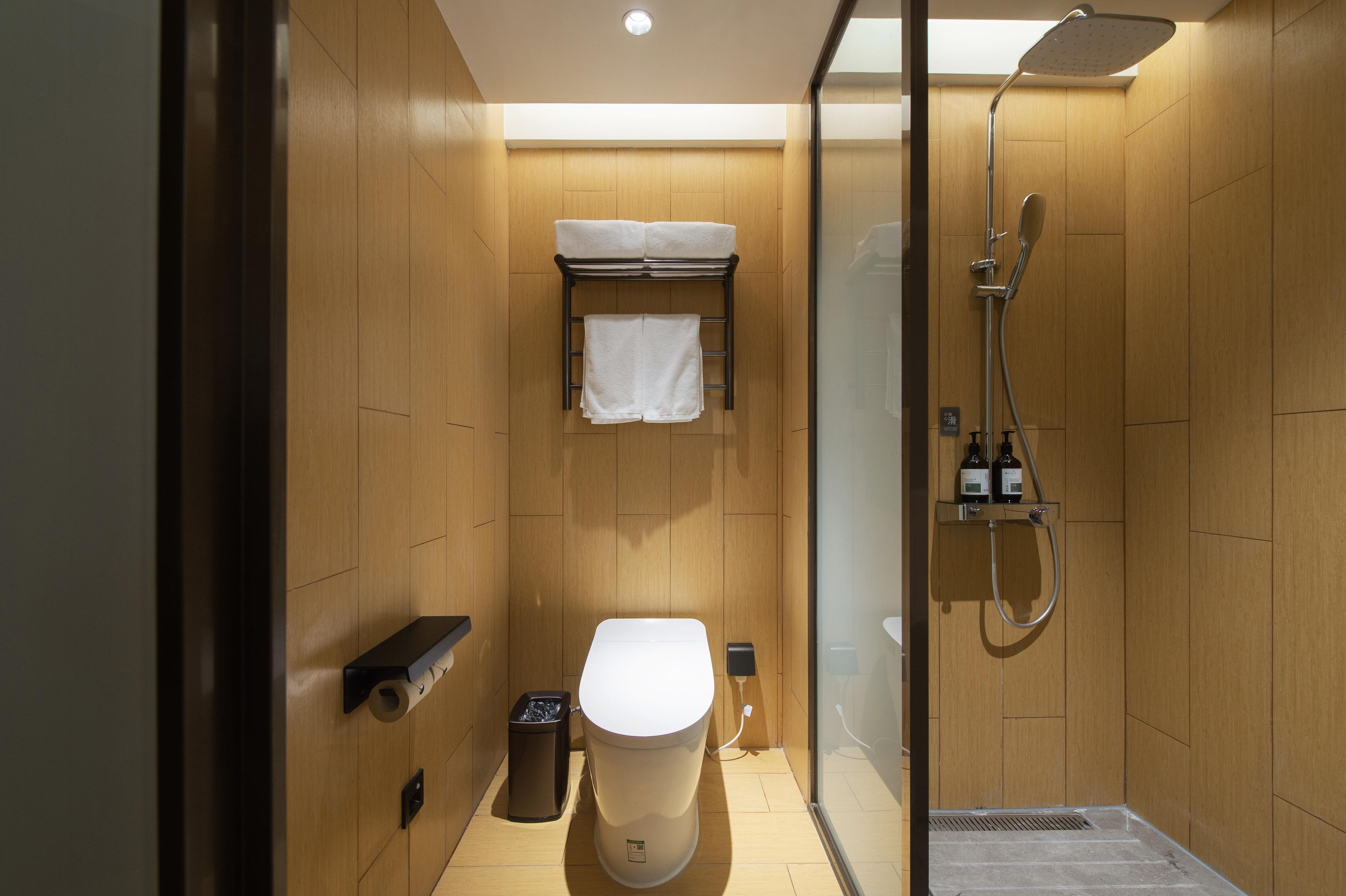 A modern bathroom with a shower, toilet, and towel rack.