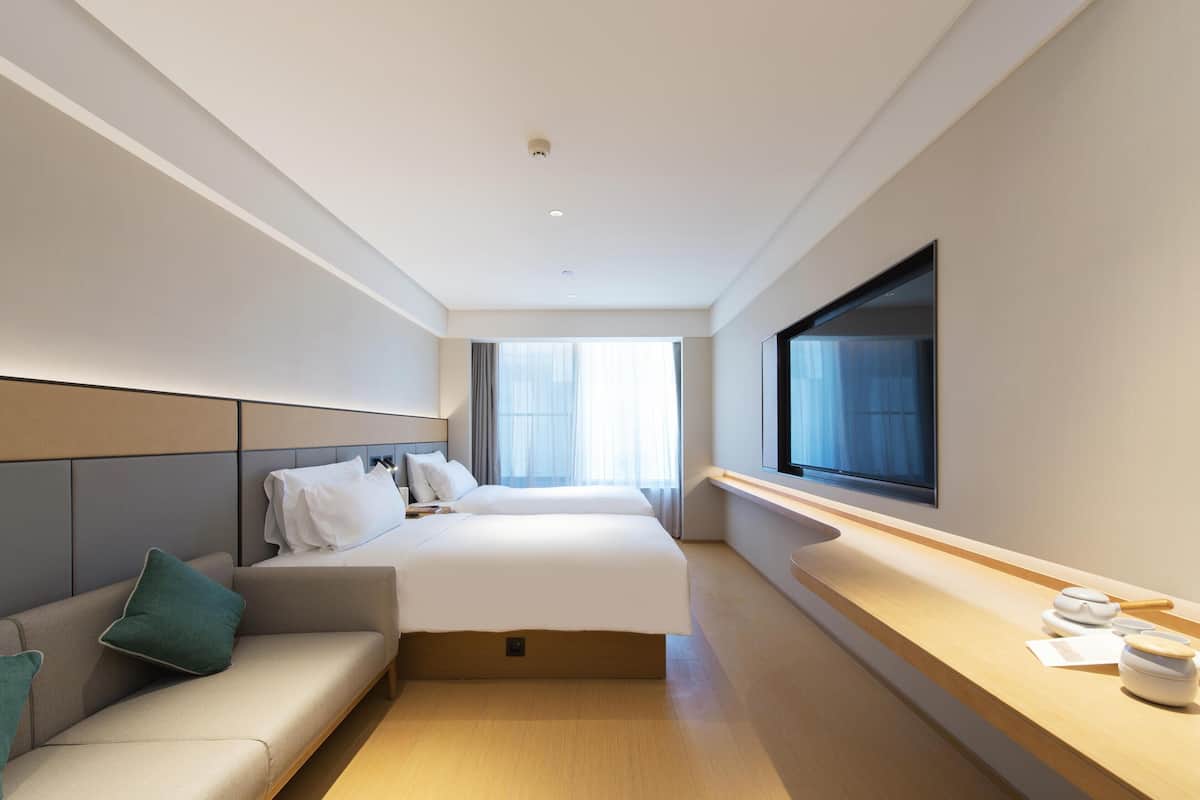 Habitación de hotel con cama, sofá, televisión y ventana.