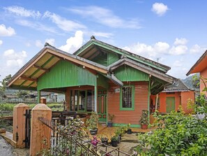 A two-story building with a green roof and a balcony, surrounded by potted plants and a metal gate. - OYO 91128 Desa Wisata Lebakmuncang Ciwidey Syariah (Ciwidey)