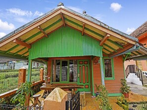 Une maison de style rustique, dotée d’un toit végétalisé et d’une structure en bois, entourée d’un jardin.