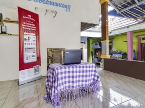 A room with a laptop on a table, a red banner, and a checkered tablecloth. - OYO 91128 Desa Wisata Lebakmuncang Ciwidey Syariah (Ciwidey)
