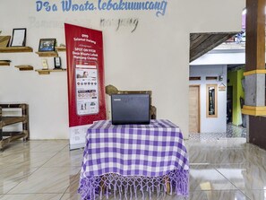 Une pièce avec une table à carreaux, un ordinateur portable et une affiche rouge accrochée au mur.