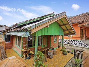 Une maison avec un toit végétalisé, une véranda dotée de bancs en bois et des plantes en pot.