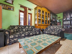A living room with a sofa set, a wooden cabinet, and a tiled floor. - OYO 91128 Desa Wisata Lebakmuncang Ciwidey Syariah (Ciwidey)