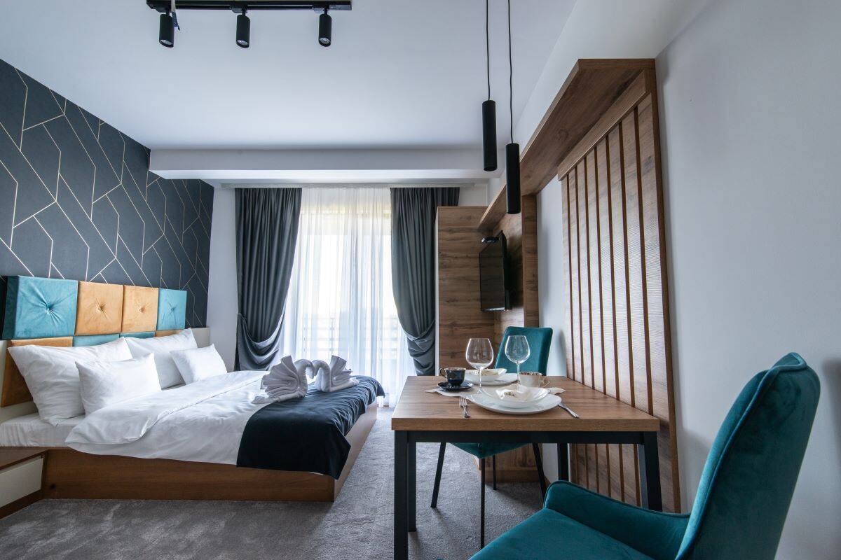 Una habitación de hotel moderna con cama, mesa de comedor y televisor.