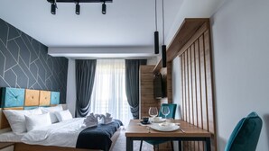 A modern hotel room with a bed, a dining table, and a TV. - Hotel Djina (Raška)