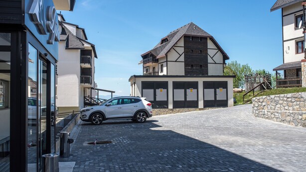 Ein modernes Gebäude mit einem geparkten Auto davor, einer Steinmauer und blauem Himmel.