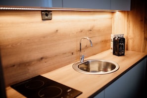 A modern kitchen with a stainless steel sink, wooden countertop, and a built-in induction cooktop.