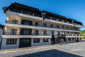 A multi-story hotel with balconies, a stone facade, and a clear sky. - Hotel Djina (Raška)