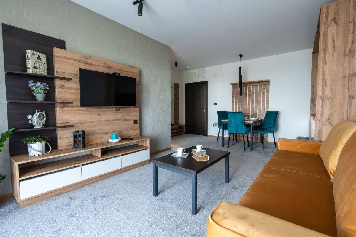 Una sala de estar moderna con televisor, sofá, mesa de centro y comedor.