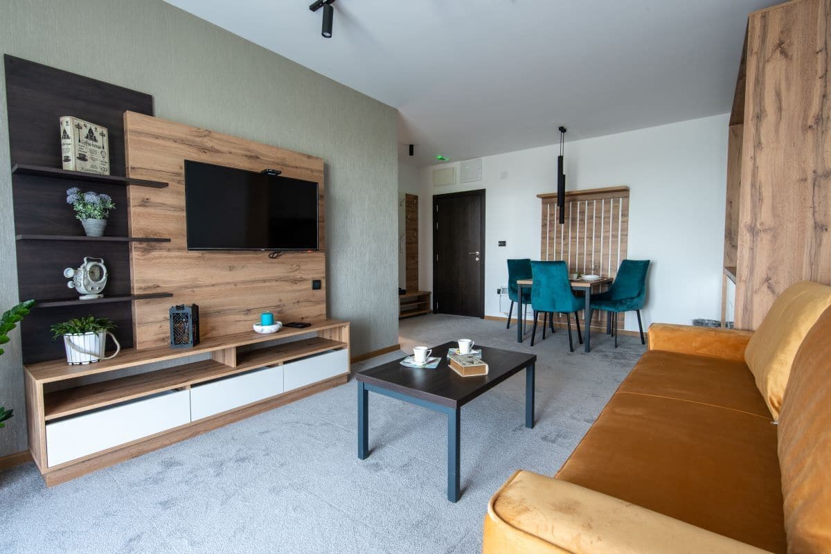 A modern living room with a TV, sofa, coffee table, and dining area.