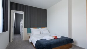Ein Schlafzimmer mit einem Bett, einem Nachttisch, einer Tür zu einem Flur und einer Wand mit vertikalen Linien.