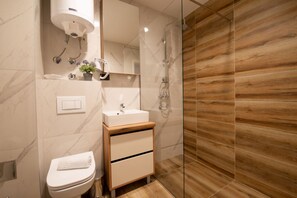 A modern bathroom with a toilet, sink, and shower.