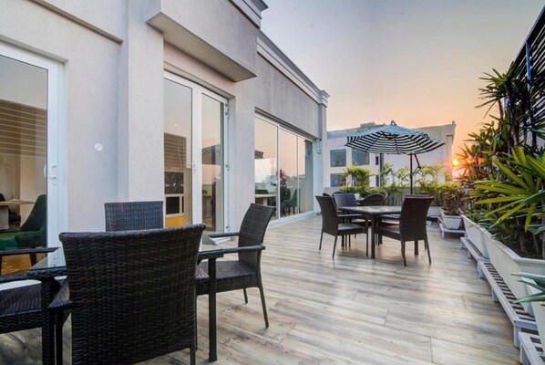 An outdoor patio with wicker furniture, a table, and chairs. - Amritara Sadka, Amritsar Golden Temple (Amritsar)