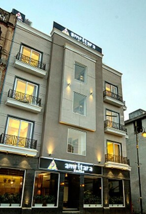 Un hotel de varios pisos con balcones, un restaurante visible y un cielo despejado.