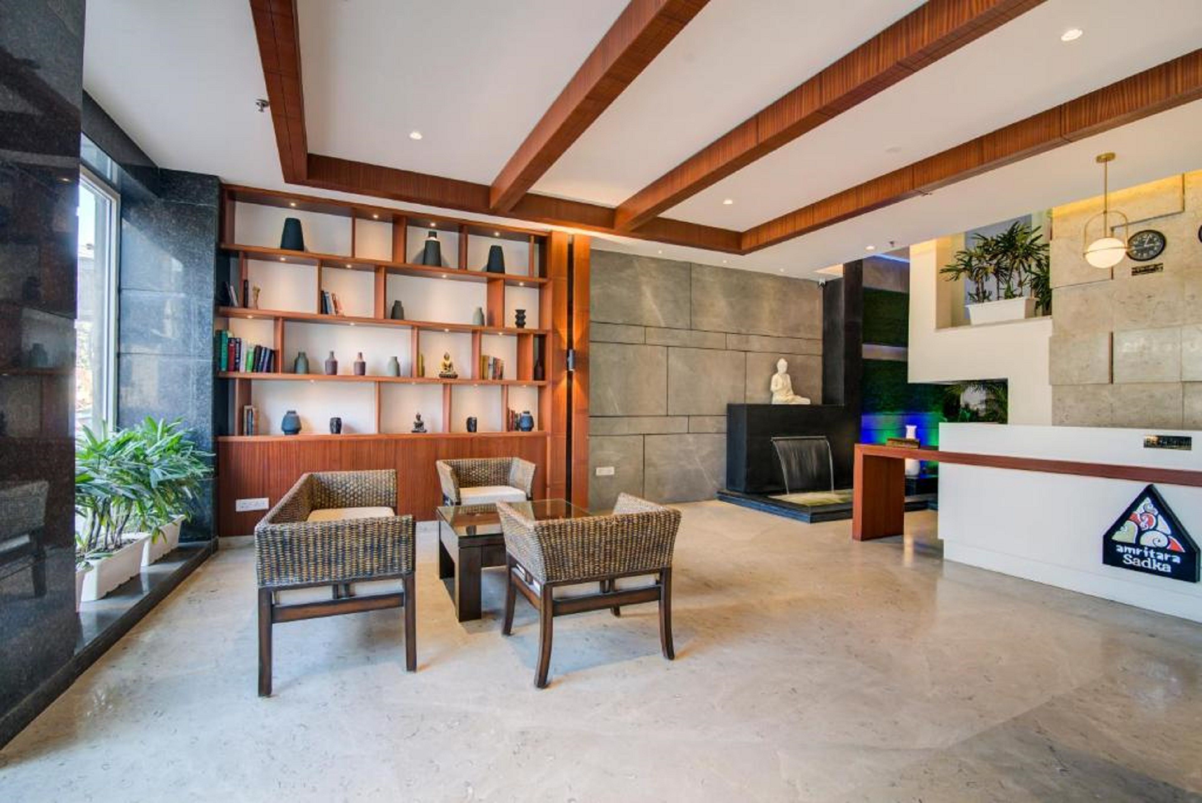 A reception area with a reception desk, wicker chairs, a bookshelf, and a stone wall.