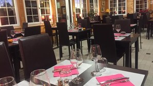 A restaurant with tables set for dining, chairs, and a view of the outside through large windows. - Logis Hotel le 1050 (Saint-Jeure-d'Andaure)